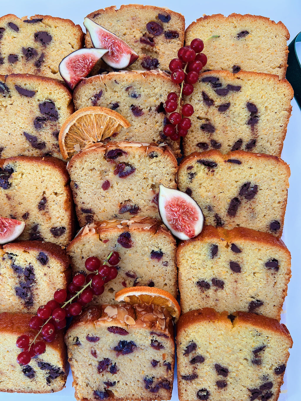 Sliced festive loaf cake platter with figs and oranges on a white background